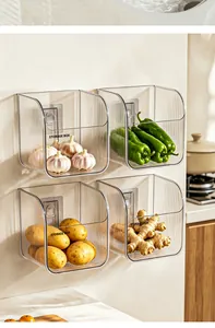 Transparent wall-mounted kitchen storage baskets holding garlic and various vegetables