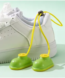 Close-up detail of boot-shaped shoe deodorizers in green and yellow on a white sneaker