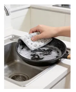 Close-up showing the absorbent thickened dishcloth cleaning a greasy frying pan in a sink.
