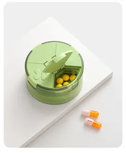 Close-up of green 4-compartment pill organizer showing open lid and medicine inside