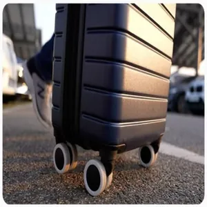 Gros plan de protections en silicone blanc pour roues de valise en extérieur.