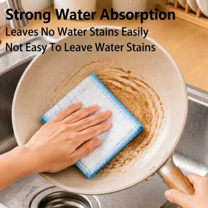 Absorbent blue checkered cotton dishcloth wiping grease from a stone-coated pan.