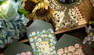 Macro view of dark green floral envelopes with gold foil and cute hamster illustrations