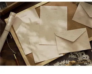 Vintage letter paper and envelope set with botanical leaf patterns under soft tree shadows.