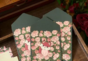 Macro detail of dark green envelopes with gold foil flower and fox illustration.