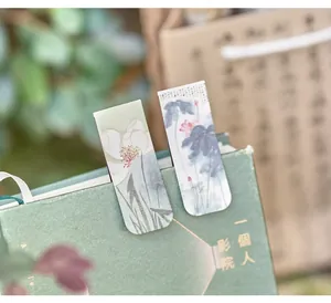 Detailed close-up showing vintage Chinese ink lotus magnetic bookmarks clipped on a green book
