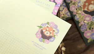 Detailed macro view of gold-stamped red panda and floral illustrations on stationery paper