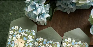 Close-up of dark green floral envelopes with cute hamster and gold foil details