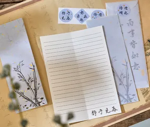 Close-up of Chinese style letter paper with calligraphy and bamboo patterned envelopes.