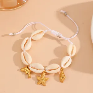 Close-up of natural cowrie shell bracelet with gold starfish and dolphin charms.