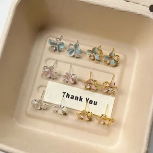 Detail of 6 pairs of flower petal enamel stud earrings in pastel blue, pink, and white tones.