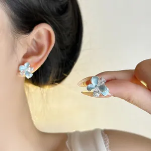 Detail of elegant light blue enamel flower stud earrings featuring a crystal center