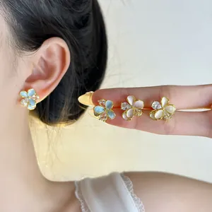 Detailed macro view of sweet enamel flower earrings in pink, blue, and white variants