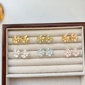 Set of pastel enamel flower stud earrings in white, blue, and pink in jewelry box.