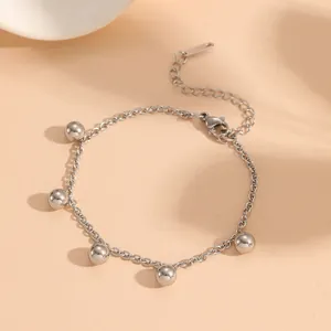 Close-up of a minimalist silver stainless steel bracelet featuring five polished ball charms