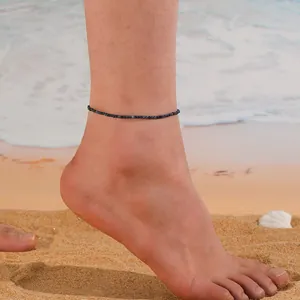 Gros plan d'un bracelet de cheville minimaliste en perles de cristal bleu sur la plage