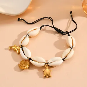 Detail of natural cowrie shell bracelet with golden sea animal charms on black cord