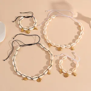 Macro detail view of a handmade shell jewelry set featuring golden fish and turtle charms