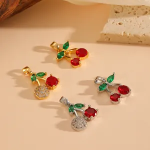 Close-up of sparkling red cherry pendants with green leaves in gold and silver finish