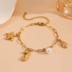 Close-up detail of gold marine charm bracelet featuring starfish, seahorse and pearl.