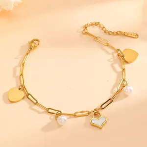 Detailed close-up view of a gold titanium steel charm bracelet with heart and pearl drops