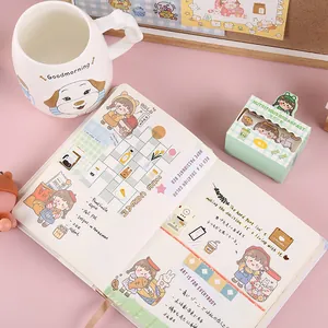 Close-up of cute cartoon girls stickers and patterned washi tape deco in a journal notebook.