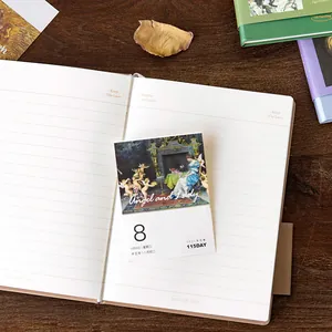 Vintage aesthetic hardcover notebook with artistic calendar page on wooden desk.