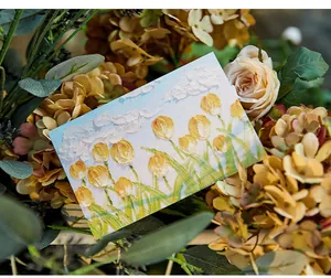 Primo piano di un biglietto di auguri con tulipani in pittura a olio tra i fiori decorativi