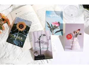 Detailansicht künstlerischer Postkarten mit Blumenmotiven auf einem offenen Buch.