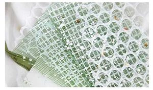 Close-up detail of vintage white lace and green mesh fabrics with gold star sequins