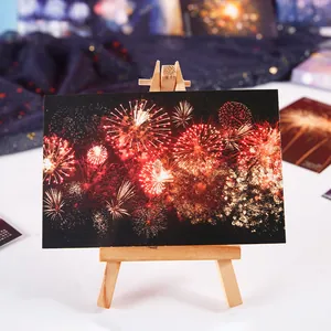 Künstlerische Postkarte mit Feuerwerksmotiv auf einer kleinen Holzstaffelei für Festgrüße.