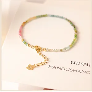 Close-up detail of 2mm rainbow tourmaline beaded bracelet with a gold heart charm