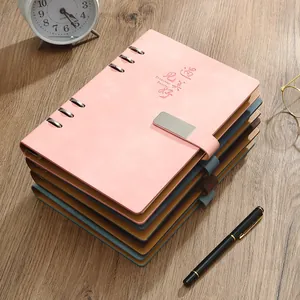 Pila de cuadernos de anillas A5 de cuero coloridos con cierre en escritorio de madera