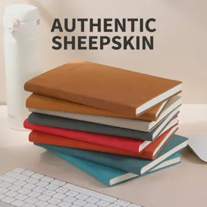 Primer plano de cuadernos de cuero A5 de colores apilados en un escritorio ordenado.
