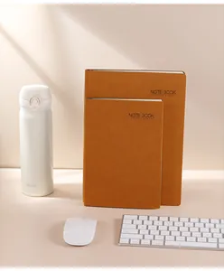 Dos cuadernos de cuero marrón en un escritorio minimalista con accesorios oficina.