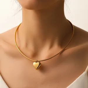 Detalle de un colgante de corazón dorado en una gargantilla de serpiente de acero 18K PVD.