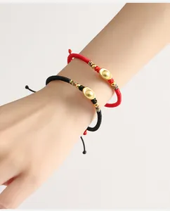 Primo piano dei braccialetti intrecciati a mano rossi e neri con ciondoli a lingotto.