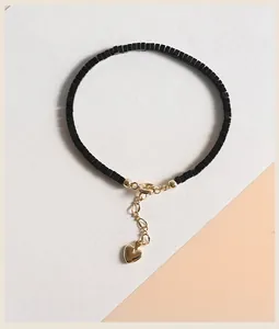 Vista dettagliata del bracciale con perline di pietra nera e ciondolo a cuore d'oro