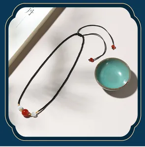 Hand-woven black cord necklace featuring red agate and white cat eye beads in a zen style