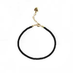 Bracciale minimalista di perle nere con ciondolo a cuore dorato e catena regolabile.
