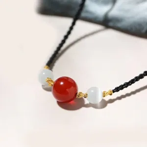 Handmade black braided rope necklace featuring red agate and white cat's eye beads