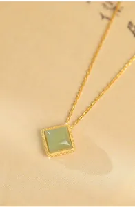 Detail view of a square green jade pendant on a delicate gold-plated silver chain