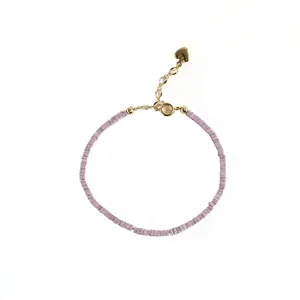 Delicate light purple mica bead bracelet with vintage gold heart charm on white background