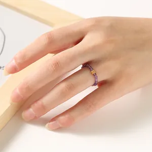 Detailed close-up of a 2mm purple amethyst beaded ring with a lucky gold coin charm
