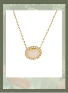 Macro shot of a vintage gold necklace with an oval white jade and pearl pendant.