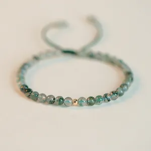 Macro view of a handmade green moss agate bracelet featuring a gold accent bead.