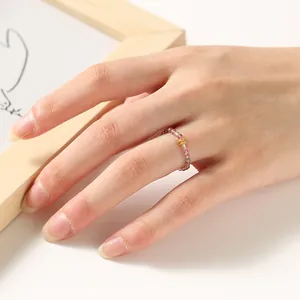 Detail shot of 2mm rainbow tourmaline beaded ring on finger with gold charm