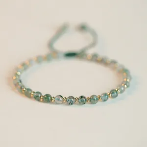 Close-up view of natural moss agate beads and gold spacers on green woven bracelet