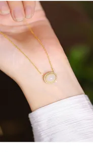 Close-up of elegant gold S925 silver necklace with oval white jade pendant on wrist