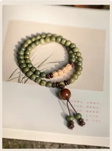 Close-up of green sandalwood Buddhist beads with natural seed accents on vintage book